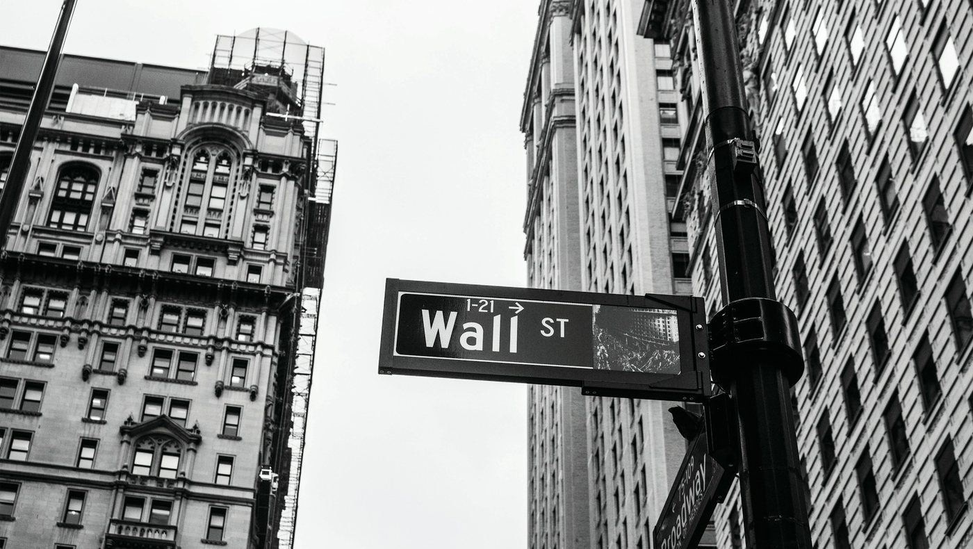 Das Straßenschild der Wall Street zwischen alten Hochhäusern in Manhattan, in Schwarz-Weiß.