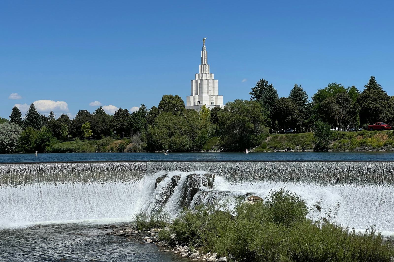 Die Fälle des Snake River am River Walk in Idaho Falls, dahinter der Mormonentempel